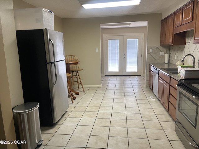 1701 S Kenser Rd, Joplin, MO 64801 - kitchen featuring stainless steel appliances, light tile patterned floors, french doors, decorative backsplash, and dark countertops