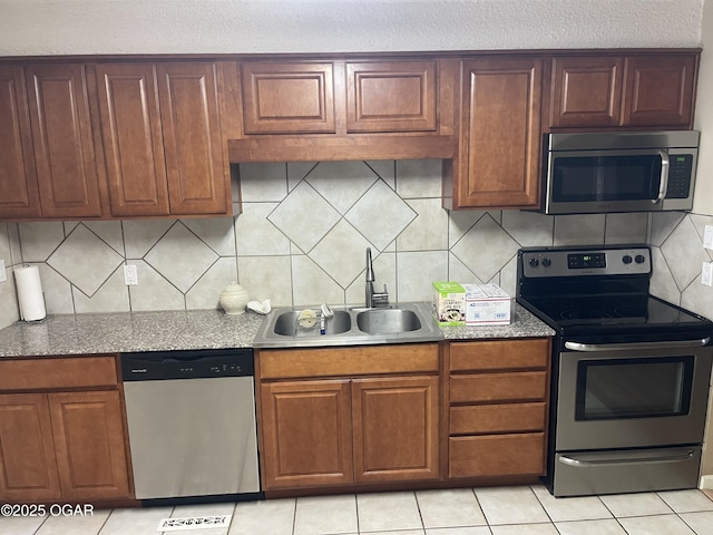 1701 S Kenser Rd, Joplin, MO 64801 - kitchen featuring appliances with stainless steel finishes, tasteful backsplash, light tile patterned floors, brown cabinets, and stone counters