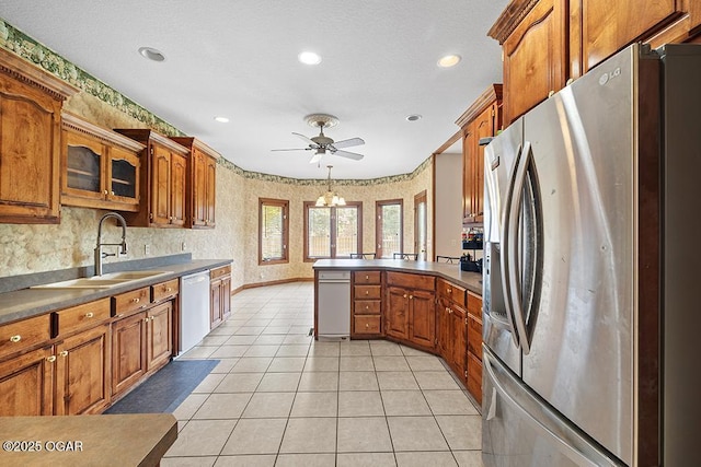 4345 Rob Ln, Joplin, MO 64804 - kitchen featuring stainless steel fridge, dishwasher, brown cabinets, a peninsula, and wallpapered walls