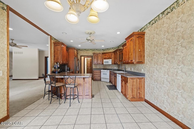 4345 Rob Ln, Joplin, MO 64804 - kitchen with ceiling fan, white appliances, a peninsula, a breakfast bar area, and recessed lighting