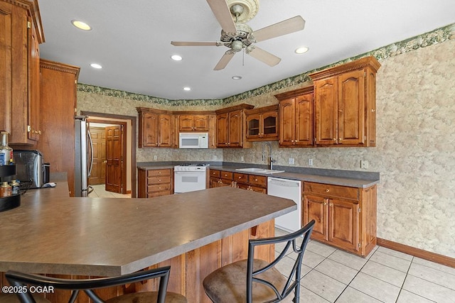 4345 Rob Ln, Joplin, MO 64804 - kitchen featuring white appliances, a peninsula, a ceiling fan, brown cabinets, and recessed lighting