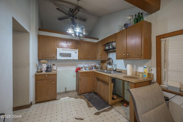 1021 Glendale Rd, Joplin, MO 64804 - kitchen with white microwave, light countertops, brown cabinets, lofted ceiling, and ceiling fan