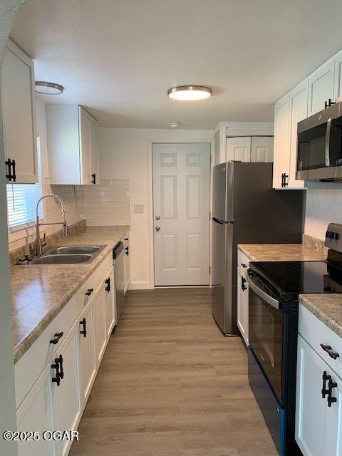 801 S Picher Ave, Joplin, MO 64801 - kitchen with stainless steel appliances, white cabinetry, light wood finished floors, and decorative backsplash