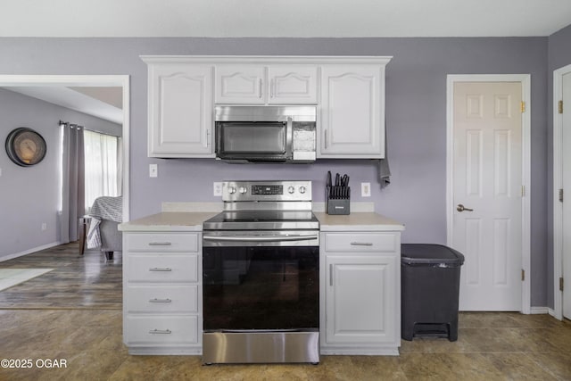 2238 Holly Ln, Miami, OK 74354 - kitchen with stainless steel appliances, white cabinetry, and light countertops