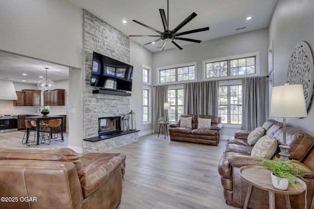 917 Monroe Cir, Carl Junction, MO 64834 - living room featuring a high ceiling, healthy amount of natural light, ceiling fan, light wood finished floors, and a stone fireplace