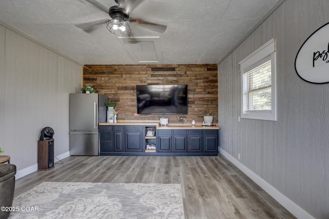 917 Monroe Cir, Carl Junction, MO 64834 - unfurnished living room with wood walls, a ceiling fan, light wood finished floors, and a textured ceiling