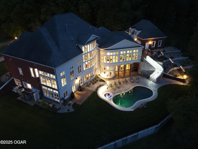 1126 Carrington Ter, Joplin, MO 64804 - back of house at night with a patio, a yard, a balcony, and an outdoor pool