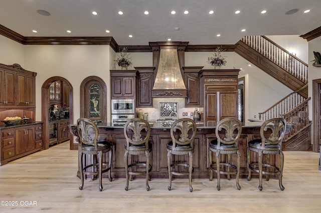 1126 Carrington Ter, Joplin, MO 64804 - kitchen featuring built in appliances, crown molding, a kitchen breakfast bar, a towering ceiling, and tasteful backsplash