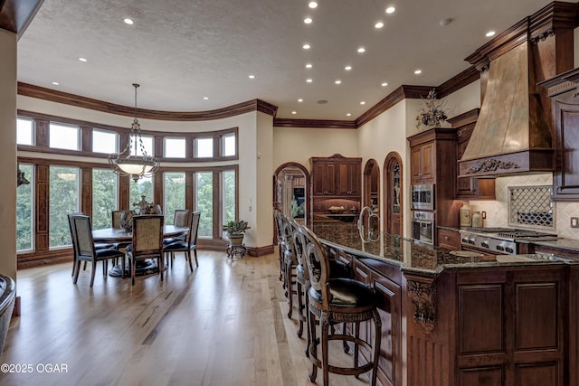 1126 Carrington Ter, Joplin, MO 64804 - kitchen with appliances with stainless steel finishes, crown molding, light wood-style flooring, recessed lighting, and dark stone counters