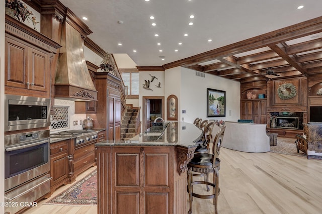 1126 Carrington Ter, Joplin, MO 64804 - kitchen featuring stainless steel appliances, a warming drawer, open floor plan, custom range hood, and light wood-type flooring
