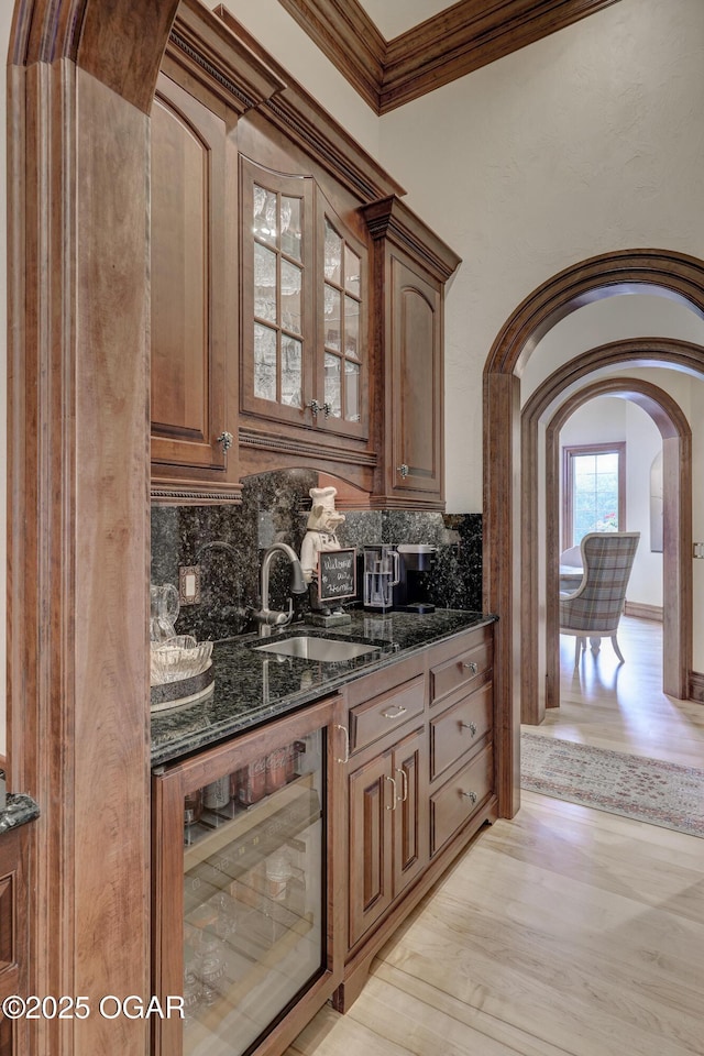 1126 Carrington Ter, Joplin, MO 64804 - kitchen featuring wine cooler, arched walkways, dark stone countertops, glass insert cabinets, and ornamental molding