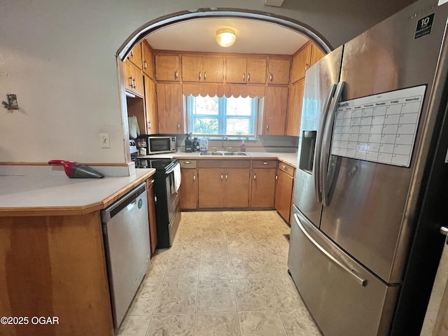 303 E Centennial Ave, Carthage, MO 64836 - kitchen featuring stainless steel appliances, arched walkways, light countertops, and brown cabinetry