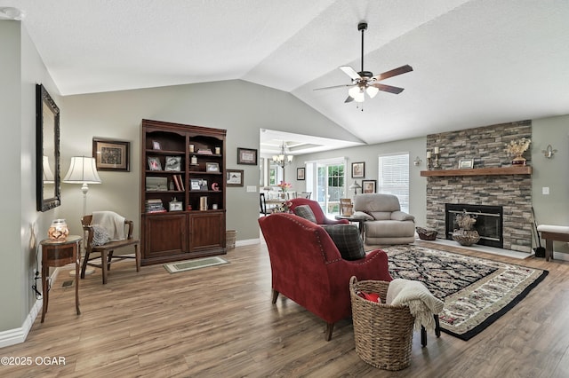 302 E 44th St, Joplin, MO 64804 - living area featuring a ceiling fan, vaulted ceiling, light wood-style flooring, a stone fireplace, and a chandelier