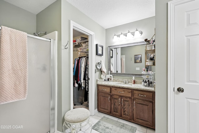 302 E 44th St, Joplin, MO 64804 - bathroom featuring a shower stall, vanity, a spacious closet, tile patterned flooring, and a textured ceiling