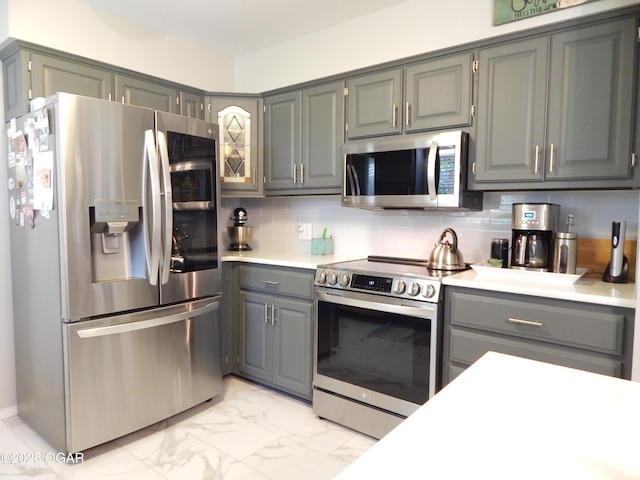 2722 E Wickersham Rd, Joplin, MO 64804 - kitchen with appliances with stainless steel finishes, decorative backsplash, light marble finish flooring, gray cabinets, and light countertops