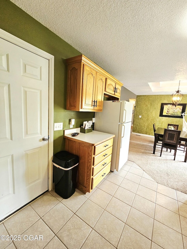 2813 Heartland Ave, Joplin, MO 64804 - kitchen with light countertops, light tile patterned floors, freestanding refrigerator, a chandelier, and a textured ceiling