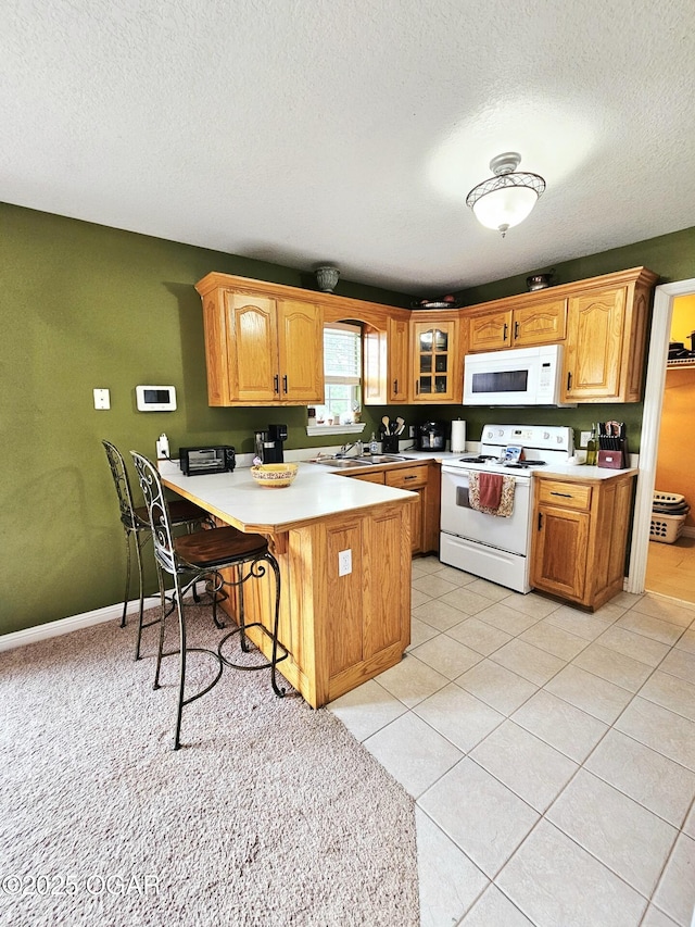 2813 Heartland Ave, Joplin, MO 64804 - kitchen with white appliances, a peninsula, a kitchen breakfast bar, light countertops, and a textured ceiling