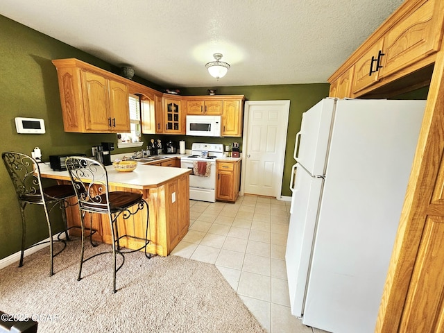 2813 Heartland Ave, Joplin, MO 64804 - kitchen featuring white appliances, a peninsula, a breakfast bar area, glass insert cabinets, and light countertops