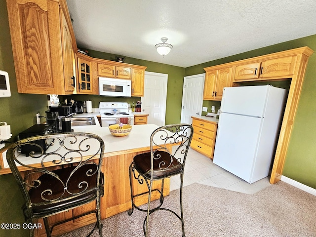 2813 Heartland Ave, Joplin, MO 64804 - kitchen featuring white appliances, a peninsula, glass insert cabinets, light countertops, and a kitchen breakfast bar