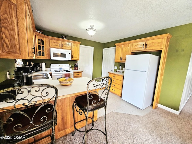 2813 Heartland Ave, Joplin, MO 64804 - kitchen featuring white appliances, a peninsula, glass insert cabinets, a kitchen breakfast bar, and light carpet