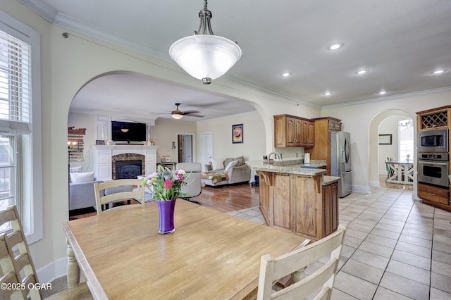 3510 Notting Hill Cir, Joplin, MO 64804 - dining area with arched walkways, a ceiling fan, crown molding, a fireplace, and light tile patterned floors