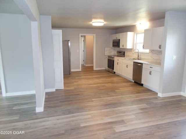 2705 S Michigan Ave, Joplin, MO 64804 - kitchen featuring stainless steel appliances, light countertops, white cabinetry, tasteful backsplash, and light wood-type flooring