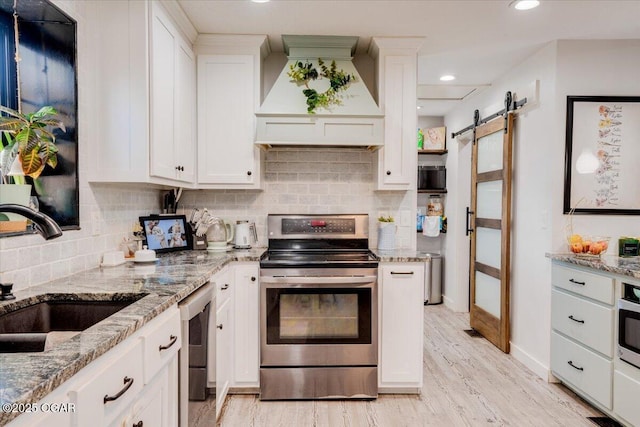 11284 Norway Rd, Neosho, MO 64850 - kitchen with stainless steel appliances, custom range hood, a barn door, white cabinets, and recessed lighting