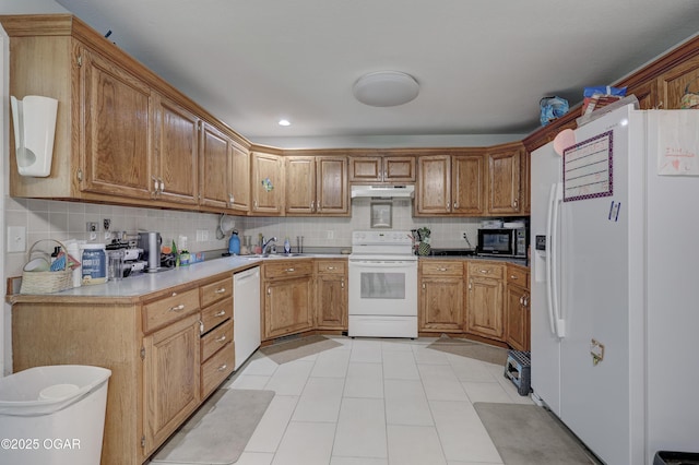 5223 County Lane 301, Joplin, MO 64801 - kitchen with white appliances, under cabinet range hood, decorative backsplash, brown cabinetry, and light countertops