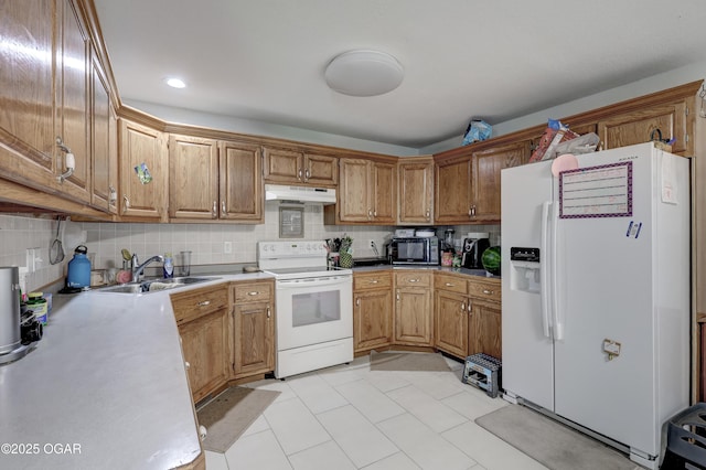 5223 County Lane 301, Joplin, MO 64801 - kitchen with white appliances, under cabinet range hood, tasteful backsplash, light countertops, and brown cabinets