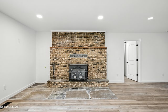 12807 Larissa Ln, Neosho, MO 64850 - unfurnished living room with a wood stove, wood finished floors, and recessed lighting