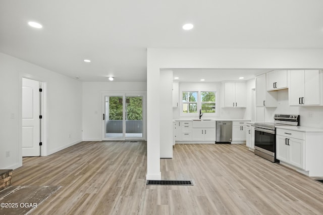 12807 Larissa Ln, Neosho, MO 64850 - kitchen with appliances with stainless steel finishes, light countertops, white cabinets, light wood-style floors, and recessed lighting