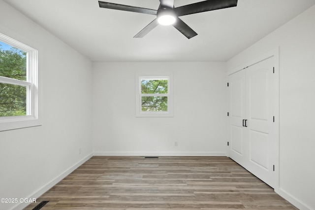 12807 Larissa Ln, Neosho, MO 64850 - unfurnished bedroom featuring multiple windows, light wood finished floors, a closet, and ceiling fan