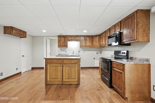3310 Tana St, Joplin, MO 64804 - kitchen featuring black appliances, light wood-style flooring, a drop ceiling, brown cabinetry, and recessed lighting