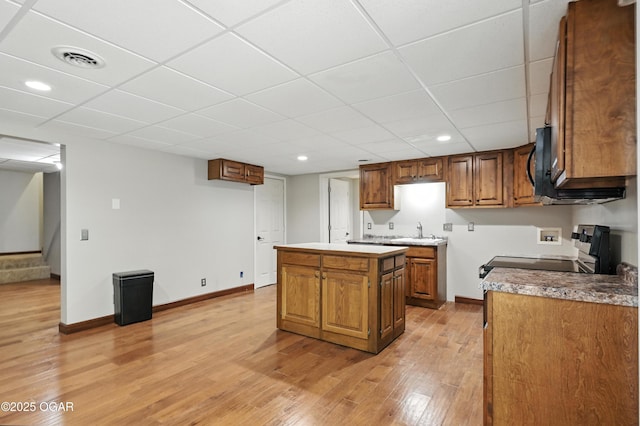 3310 Tana St, Joplin, MO 64804 - kitchen featuring range with electric stovetop, light wood-style floors, brown cabinetry, a paneled ceiling, and a kitchen island