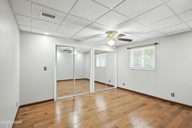 3310 Tana St, Joplin, MO 64804 - unfurnished bedroom featuring multiple closets, a drop ceiling, hardwood / wood-style floors, and a ceiling fan