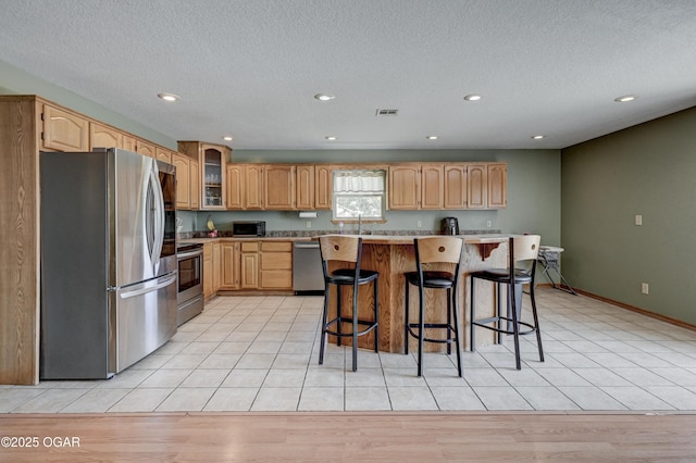 121 Fawn Trl, Seneca, MO 64865 - kitchen with stainless steel appliances, a kitchen breakfast bar, glass insert cabinets, light countertops, and a textured ceiling
