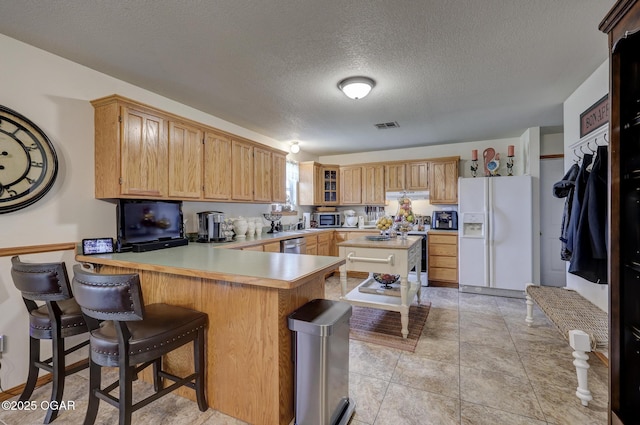 23841 Jaguar Rd, Oronogo, MO 64855 - kitchen with appliances with stainless steel finishes, a peninsula, light countertops, a textured ceiling, and a kitchen island