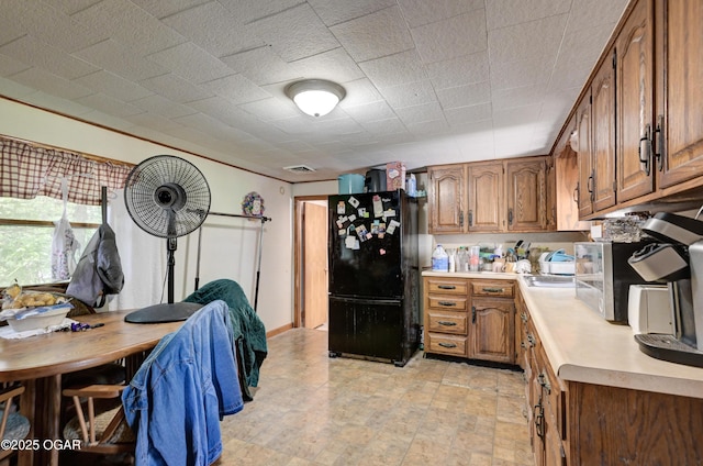 712 Joplin St, Sarcoxie, MO 64862 - kitchen featuring freestanding refrigerator, light countertops, and brown cabinets