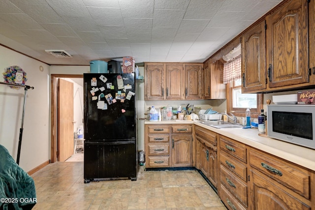 712 Joplin St, Sarcoxie, MO 64862 - kitchen featuring freestanding refrigerator, brown cabinetry, and light countertops