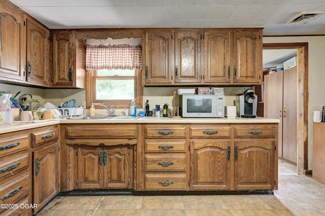 712 Joplin St, Sarcoxie, MO 64862 - kitchen featuring white microwave, brown cabinetry, light countertops, and light stone finish flooring