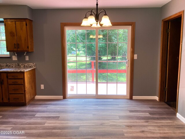 1212 W 12th St, Joplin, MO 64801 - unfurnished dining area featuring a chandelier, plenty of natural light, and wood finished floors