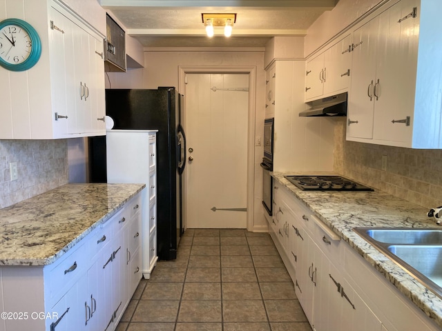 25399 Demott Dr, Joplin, MO 64801 - kitchen with black appliances, under cabinet range hood, decorative backsplash, white cabinets, and tile patterned floors