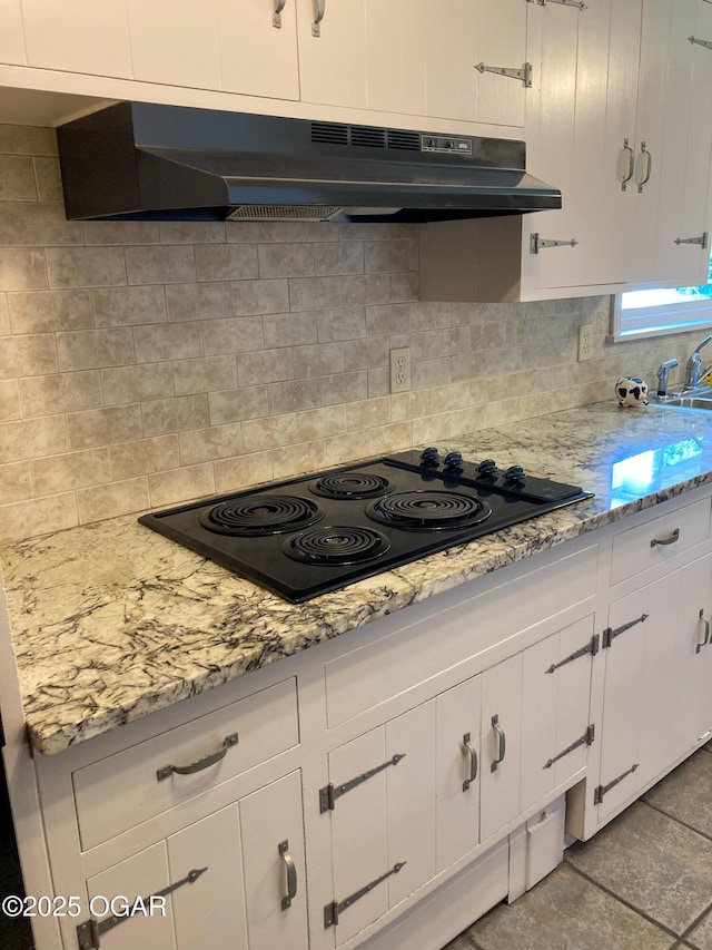 25399 Demott Dr, Joplin, MO 64801 - kitchen with under cabinet range hood, black electric cooktop, backsplash, white cabinets, and light stone counters