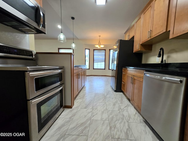 3511 Nola Dr, Joplin, MO 64801 - kitchen featuring appliances with stainless steel finishes, light marble finish flooring, dark countertops, hanging light fixtures, and brown cabinets