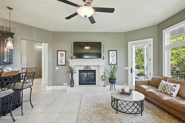 5738 Deer Park Ln, Joplin, MO 64804 - living room featuring light tile patterned floors, ceiling fan, a glass covered fireplace, and a chandelier