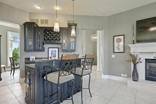 5738 Deer Park Ln, Joplin, MO 64804 - kitchen with a breakfast bar, glass insert cabinets, light tile patterned floors, and pendant lighting