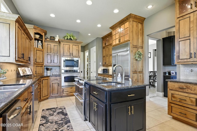 5738 Deer Park Ln, Joplin, MO 64804 - kitchen featuring built in appliances, an island with sink, decorative backsplash, recessed lighting, and dark stone countertops