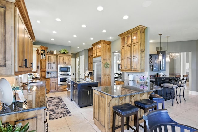 5738 Deer Park Ln, Joplin, MO 64804 - kitchen featuring built in appliances, light tile patterned floors, a kitchen island with sink, dark stone countertops, and recessed lighting