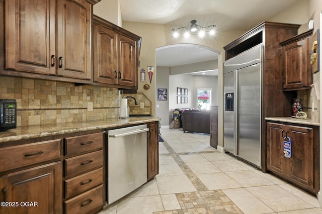 5738 Deer Park Ln, Joplin, MO 64804 - kitchen with stainless steel appliances, arched walkways, tasteful backsplash, light tile patterned floors, and light stone countertops