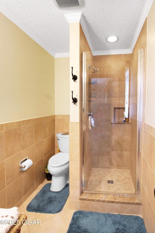 3508 Dirr Ave, Parsons, KS 67357 - full bathroom featuring a textured ceiling, tile walls, a stall shower, tile patterned flooring, and wainscoting